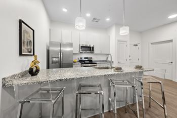 A modern kitchen with a granite countertop and stainless steel appliances. at The Lumos Apartments, Ohio